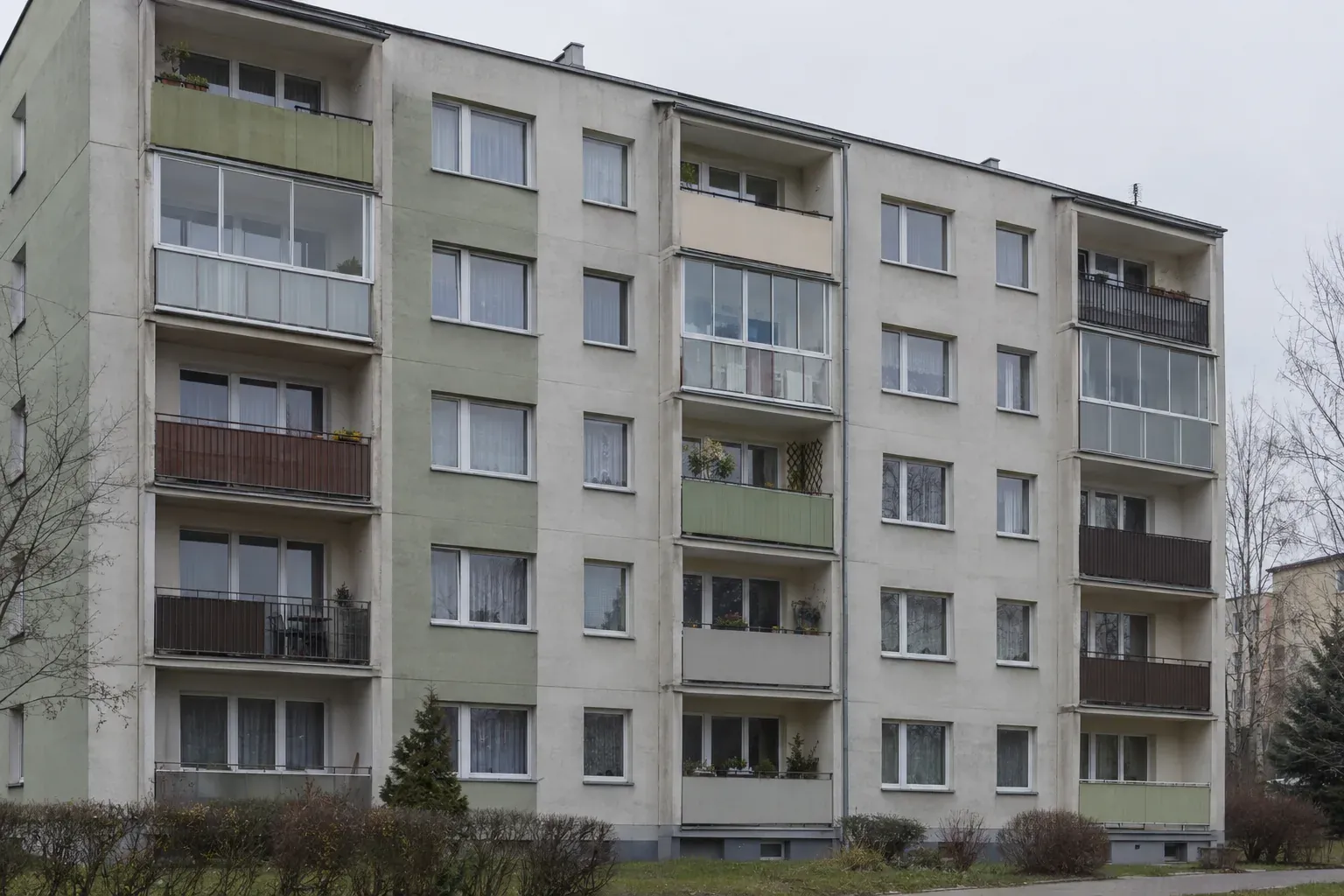 Fasada budynku wielorodzinnego z kilkoma balkonami na jednym piętrze, część z nich przeszklona